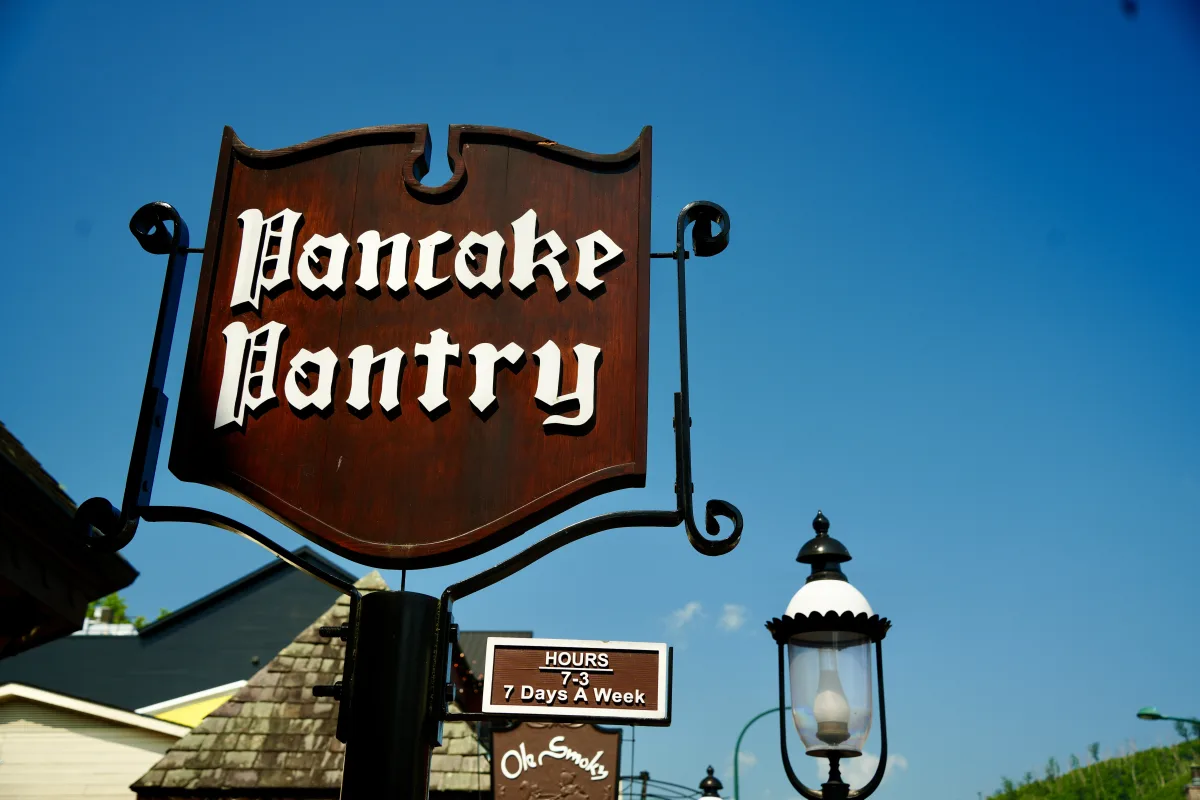 Wooden sign with "Pancake Pantry" in white lettering, clear blue sky, street lamp nearby. at Pancake Pantry in Gatlinburg